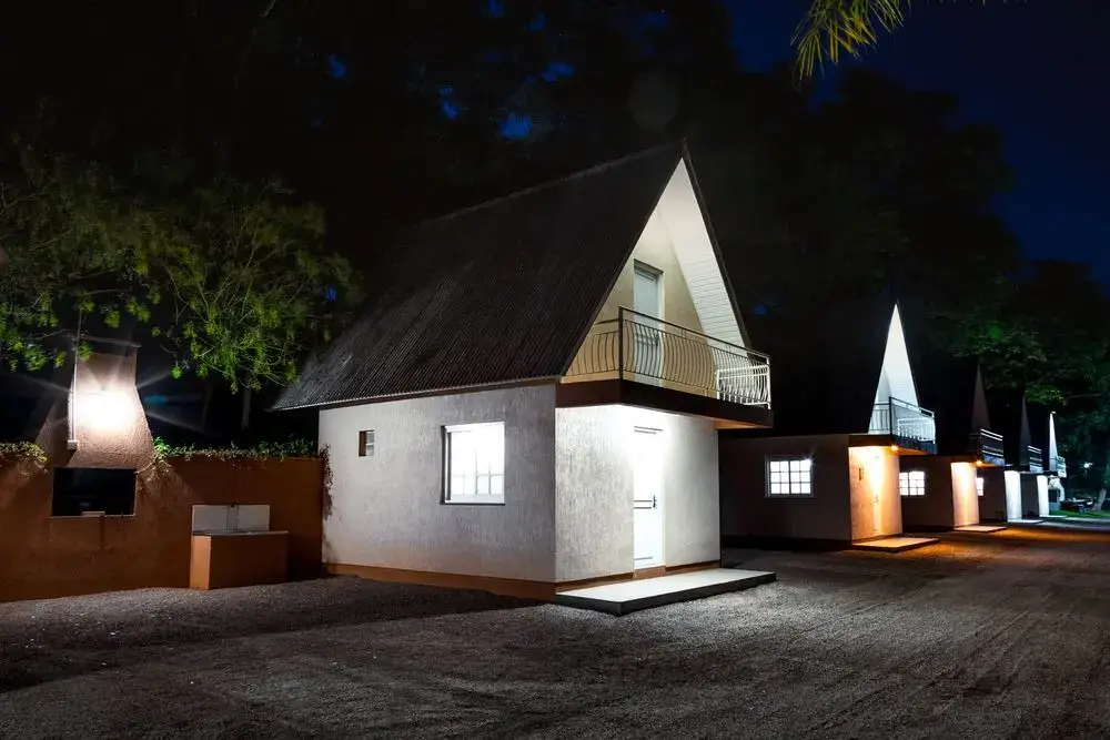 Cabana iluminada à noite, com sacada e churrasqueira ao lado