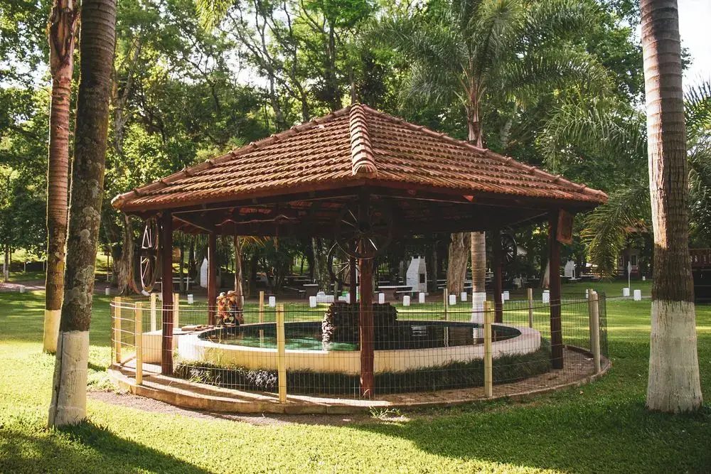 Gazebo de telhado de telha sobre um chafariz, entre palmeiras