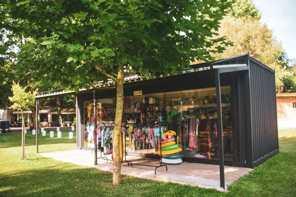 Loja de utilidades com vitrine de roupas e boias, no gramado